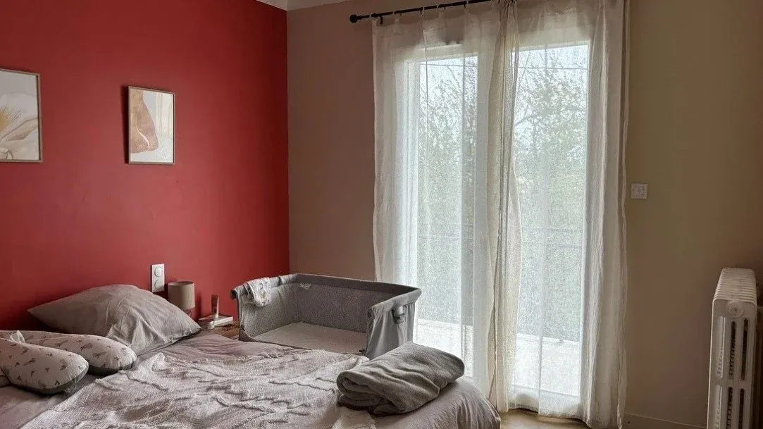 Chambre avant : mur rouge et lit encombré