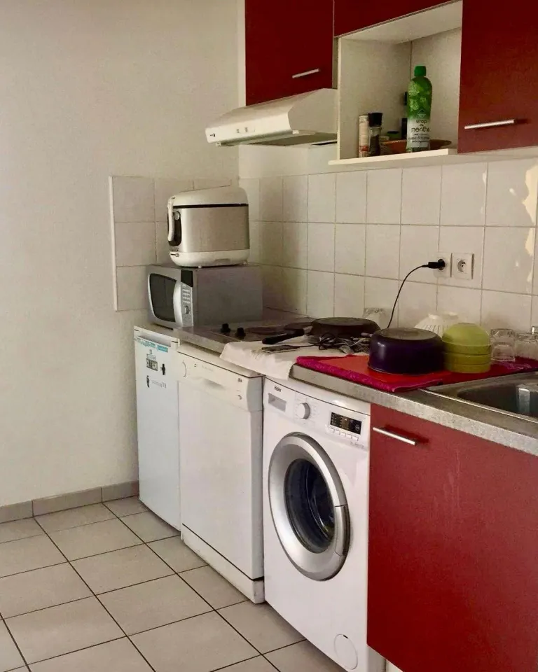 Cuisine avant : meubles rouges et électroménager apparent